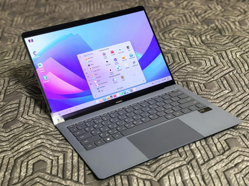 A sleek modern laptop with an open application menu on a patterned surface.